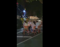 People dine outside by garbage truck