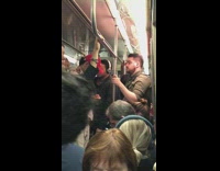 Guy in scary face jacket rolls a joint on crowded subway train and smokes