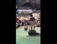 Man on rock paddles for beach video
