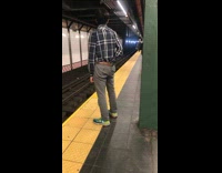 Guy blue plaid shirt picks his pants and scratches butt in subway station