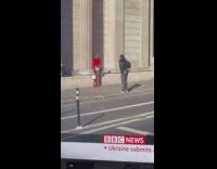 Woman in red top poses behind the news reporter on TV Part 2