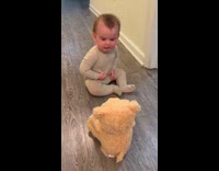Baby on floor scared of peekaboo bear