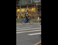 Man on blue citi bike balances ball on head