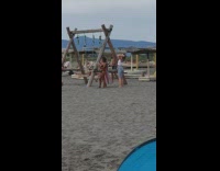 Woman in black bra walkover and bends at the beach