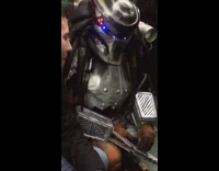 man talking to guy dressed in predator costume on train