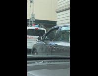 Driver of gray van plays drums using dashboard with red drumsticks while driving