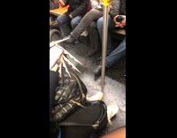 Woman scrolls on phone with long white nails on subway train