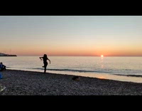 Woman dances by the beach at sunset