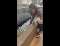 Woman filling cup in lobby fountain to flush toilet