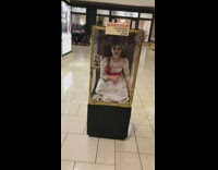 Girl wears doll inside glass case costume