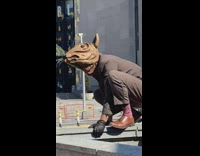 Rat costume guy squats on concrete wall 
