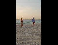 Woman blue top tiptoed pose at beach