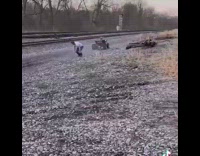 Guy falls off ATV while doing a wheelie next to tracks 