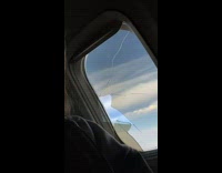 Girl on plane sitting next to broken window 