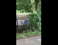 Guy facing black gate plays the saxophone 