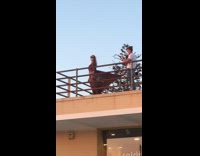 Woman brown dress skirt held by photographer on balcony