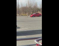 girl sits on red car empty lot