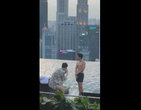 Guy poses by pool and city skyline 