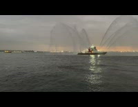 Guy swimming in water while FDNY boat shoots water out 