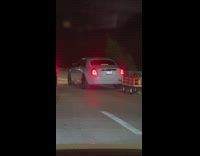 White car drives pulling tiny wagon 