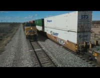 Shipping containers being transported beside stopped train