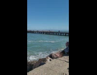 Two girls jump and swing arms pier