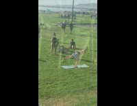 Girl films kettlebell exercise at busy park 