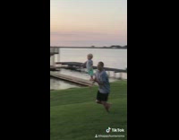 Dad runs with little boy standing on his hand around grass sunset 