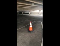 Man flips orange traffic cone and lands it perfectly on top of cone stack in parking structure