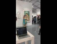 Woman holds book in front of Marilyn Monroe painting and takes picture