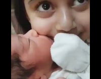Newborn baby kisses and sucks on big sisters cheek