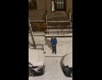 Man blue jacket juggles snowballs on sidewalk