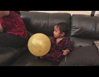 Baby boy tries to bite gold balloon 
