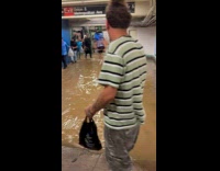 Collab WINY - Man hold shoes walk barefoot in flooded station