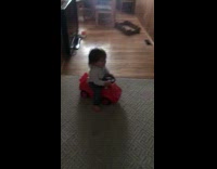 small kid on red toy motorcycle falls back