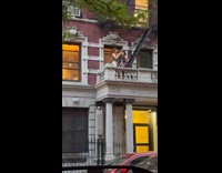 Woman gets haircut from friend at balcony