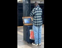 [third party - video] Man watches vlog on laptop at subway
