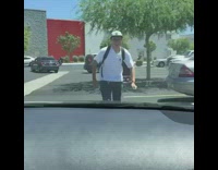 Guy runs on top of car, kicks and breaks front window glass shatters everywhere