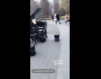 Guy plays grand piano with people laying under piano at the park