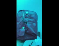 Guy holds red bag under blue light 