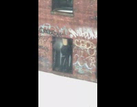 man dancing on windowsill with bag on head