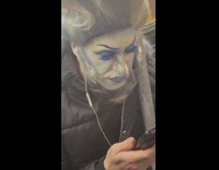 Woman sits in train with tall wig 