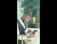 Guy in formal clothes sits at dinner table and makes funny faces at his phone on facetime