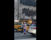 Woman holds drink and takes picture in middle of street 
