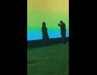 Girl black coat beside large screen grass