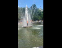 Guy washes himself in the middle of water fountain at park 
