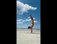 Guy does backflip into handstand at beach