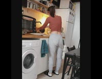 White kitten climbs girl standing in kitchen 
