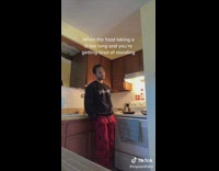 Guy bends over on counter of kitchen cooking