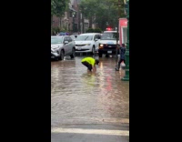 Man unclogging drainage to lessen flood on street 